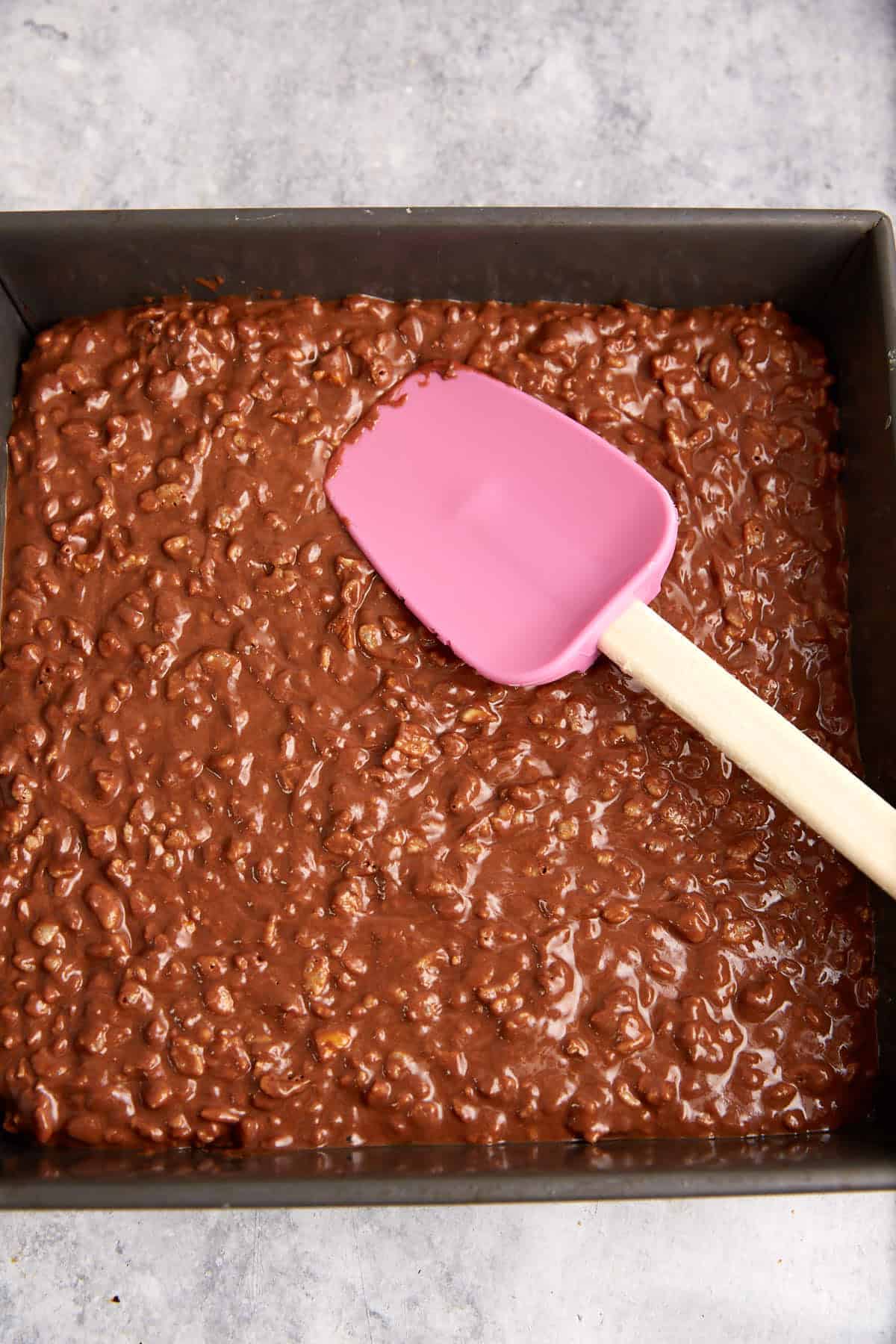Rice krispie treats spread into a baking pan.