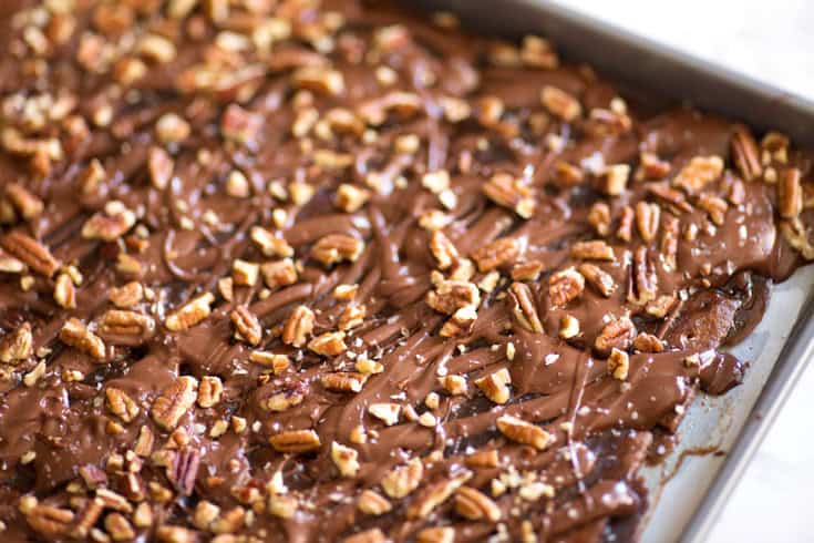 Caramel bark in a sheet pan covered with pecans.