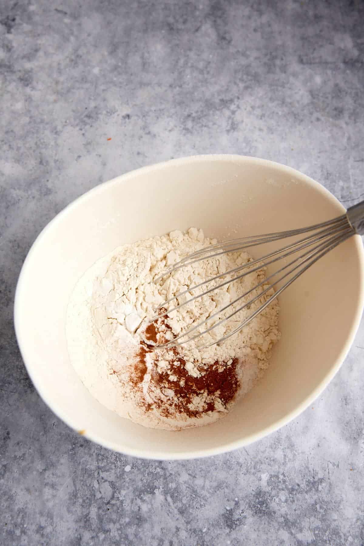 Dry ingredients in a bowl with a whisk.