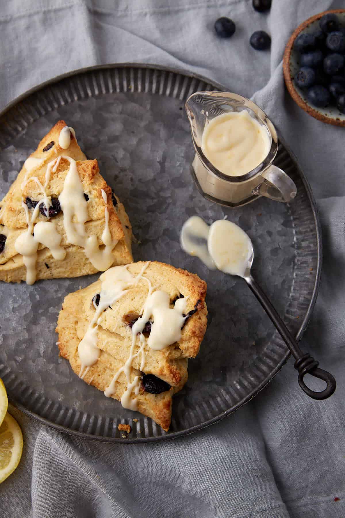 Two blueberry scones drizzled with lemon glaze.