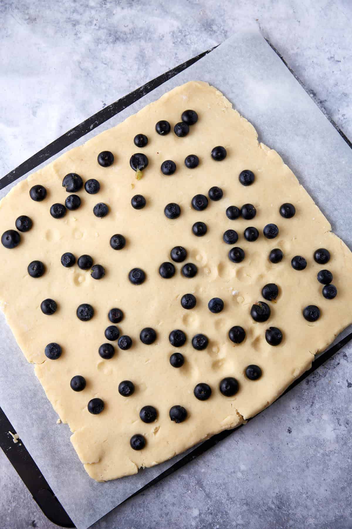 Scone dough rolled out with blueberries on top.