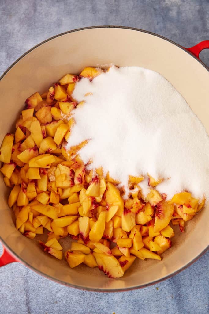 Sugar and cut peaches in a pot.