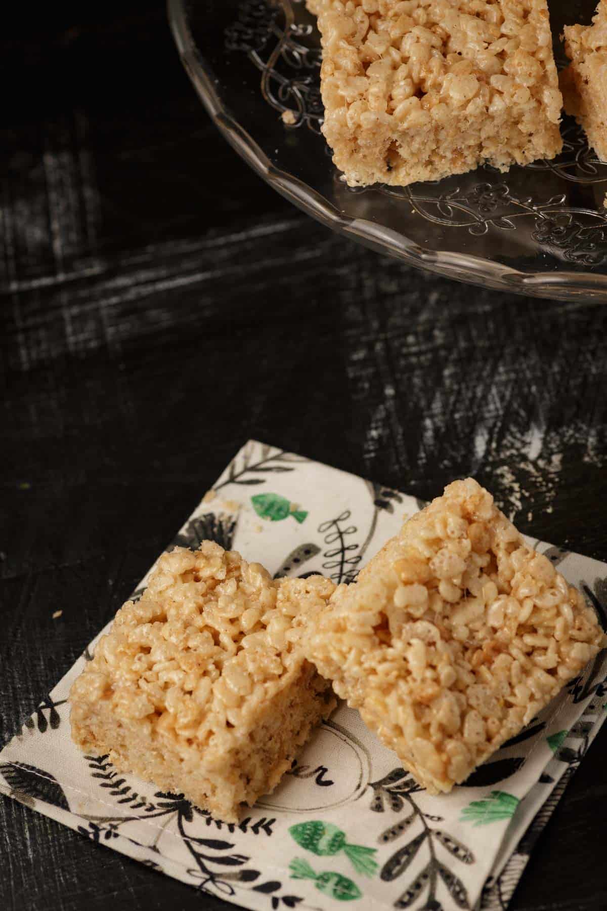 Two brown butter rice krispie treats on a napkin.