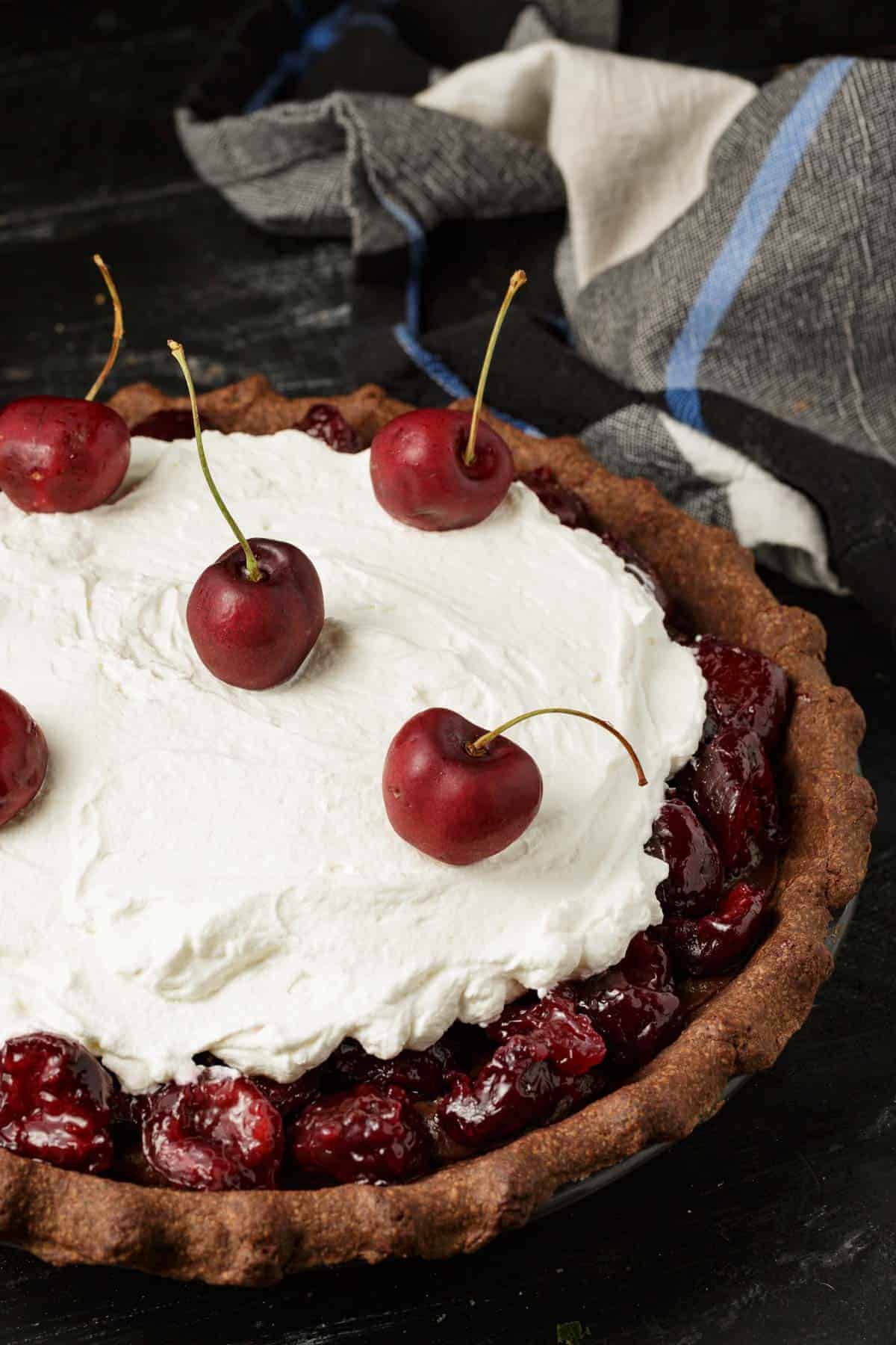 A black Forest Pie topped with fresh cherries.