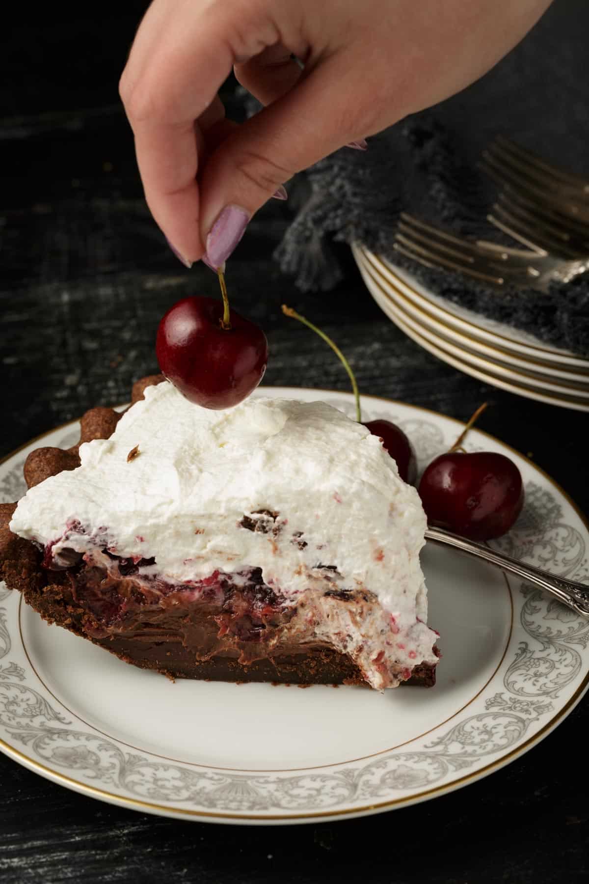 A cherry being added to a slice of pie.