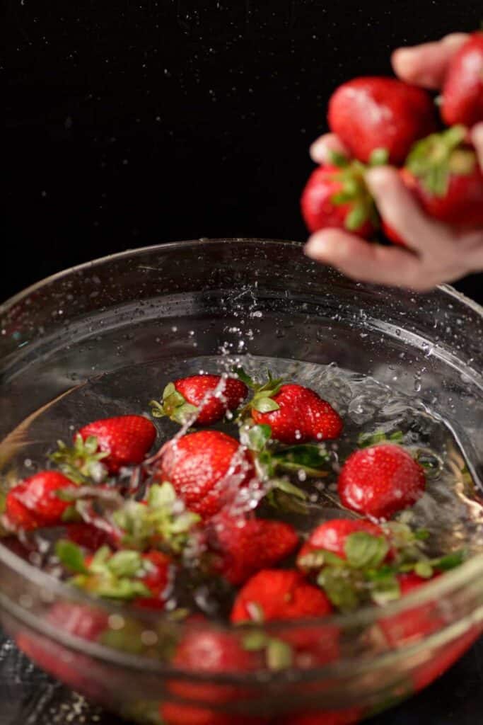 Strawberries being placed in a vinegar water bath.