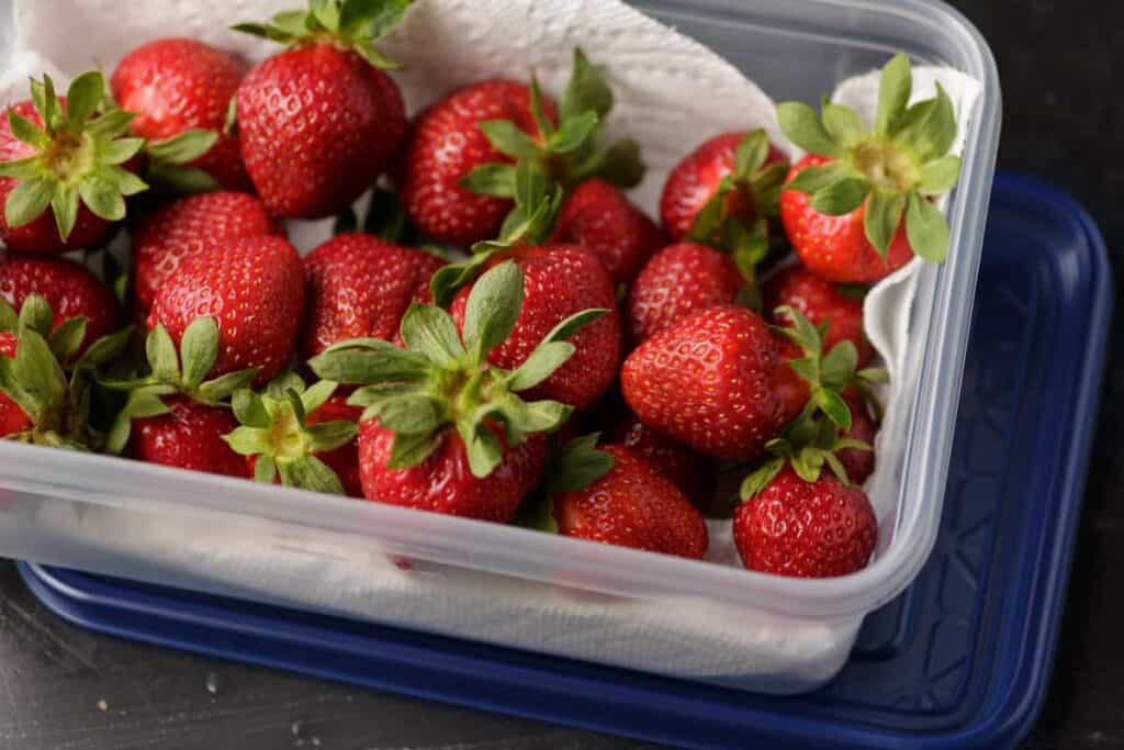 Rinsed strawberries in a paper towel lined container.