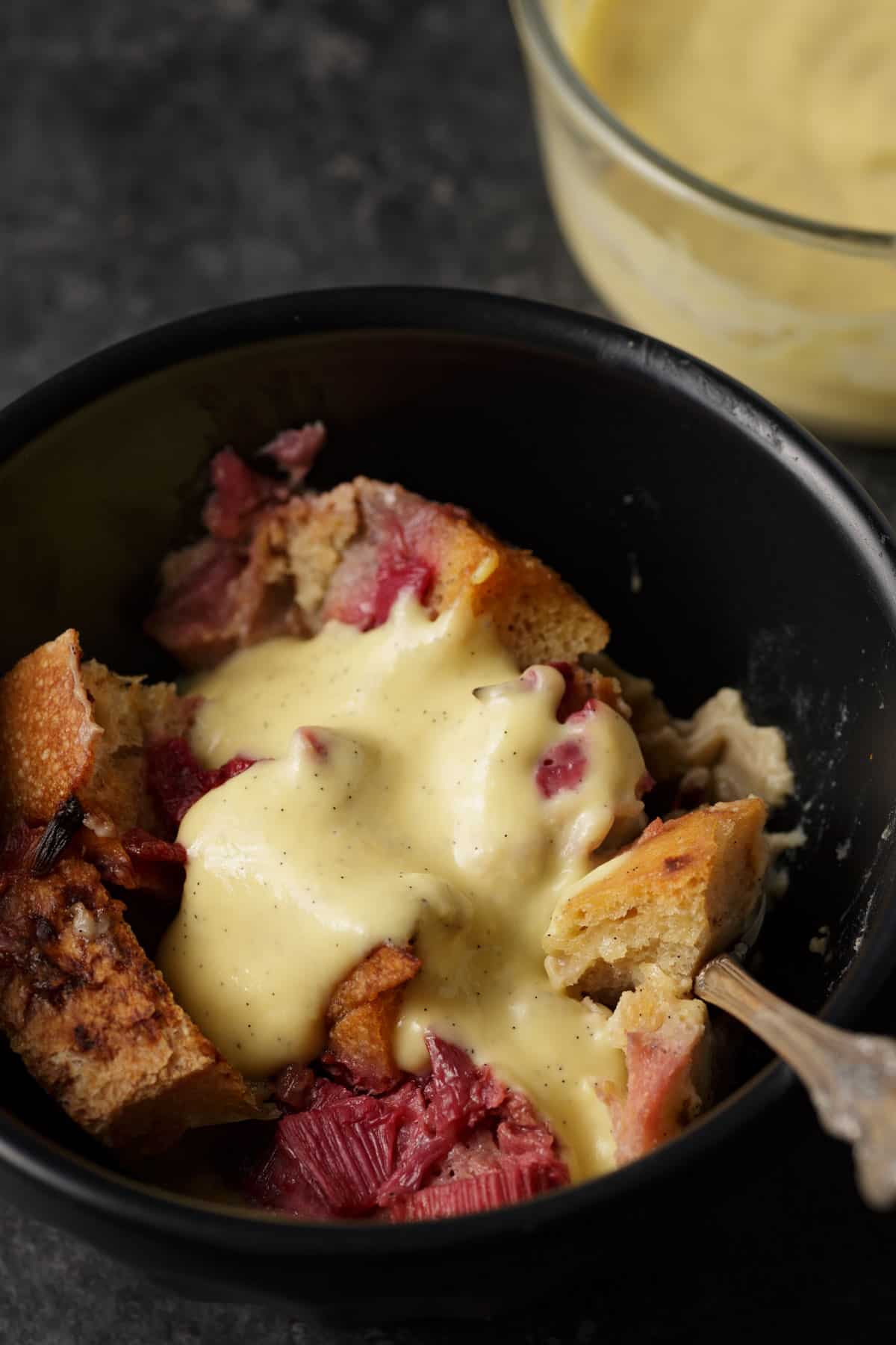 A bowl of rhubarb bread pudding with sauce.