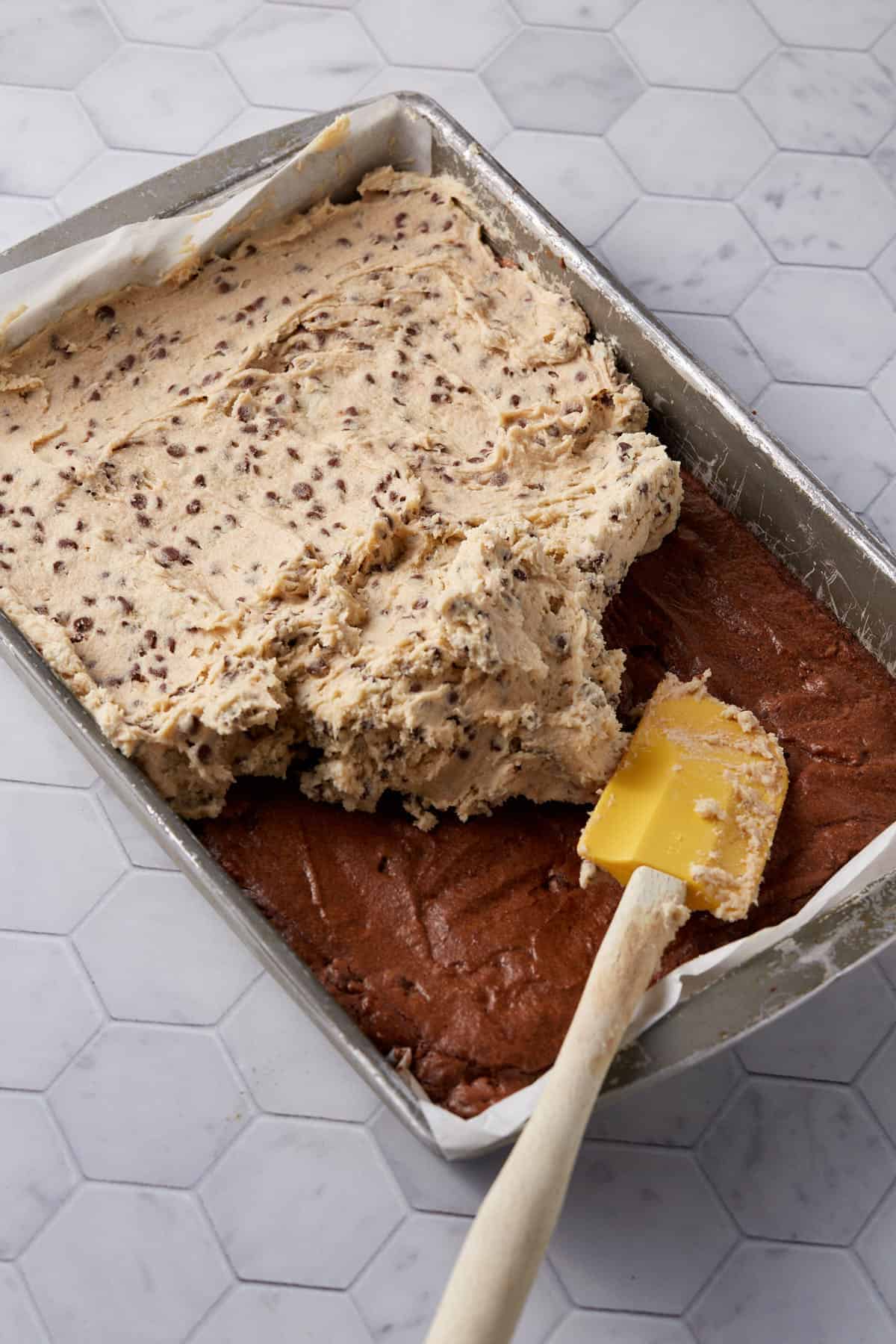 Frosting being spread over the brownies.