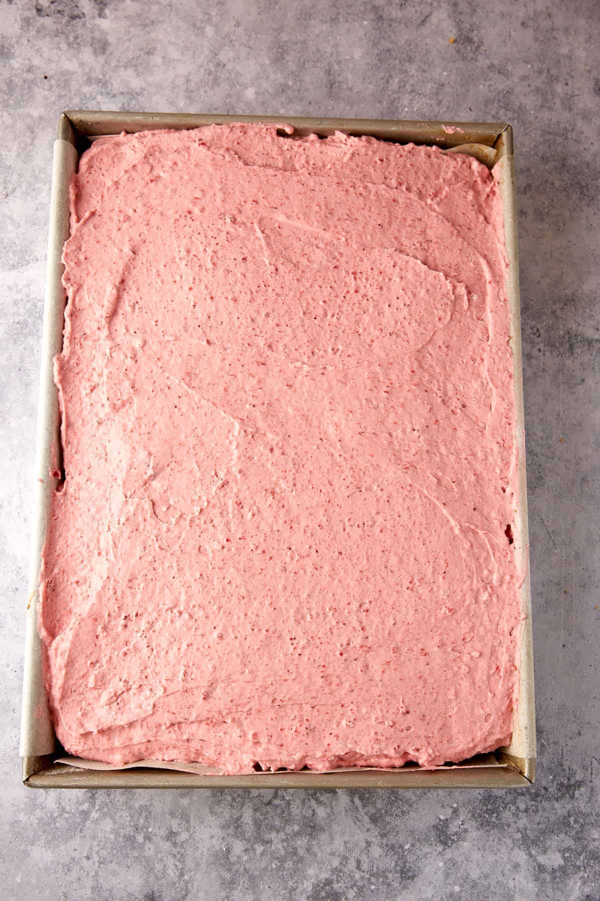 Strawberry mousse covering a sheet cake.