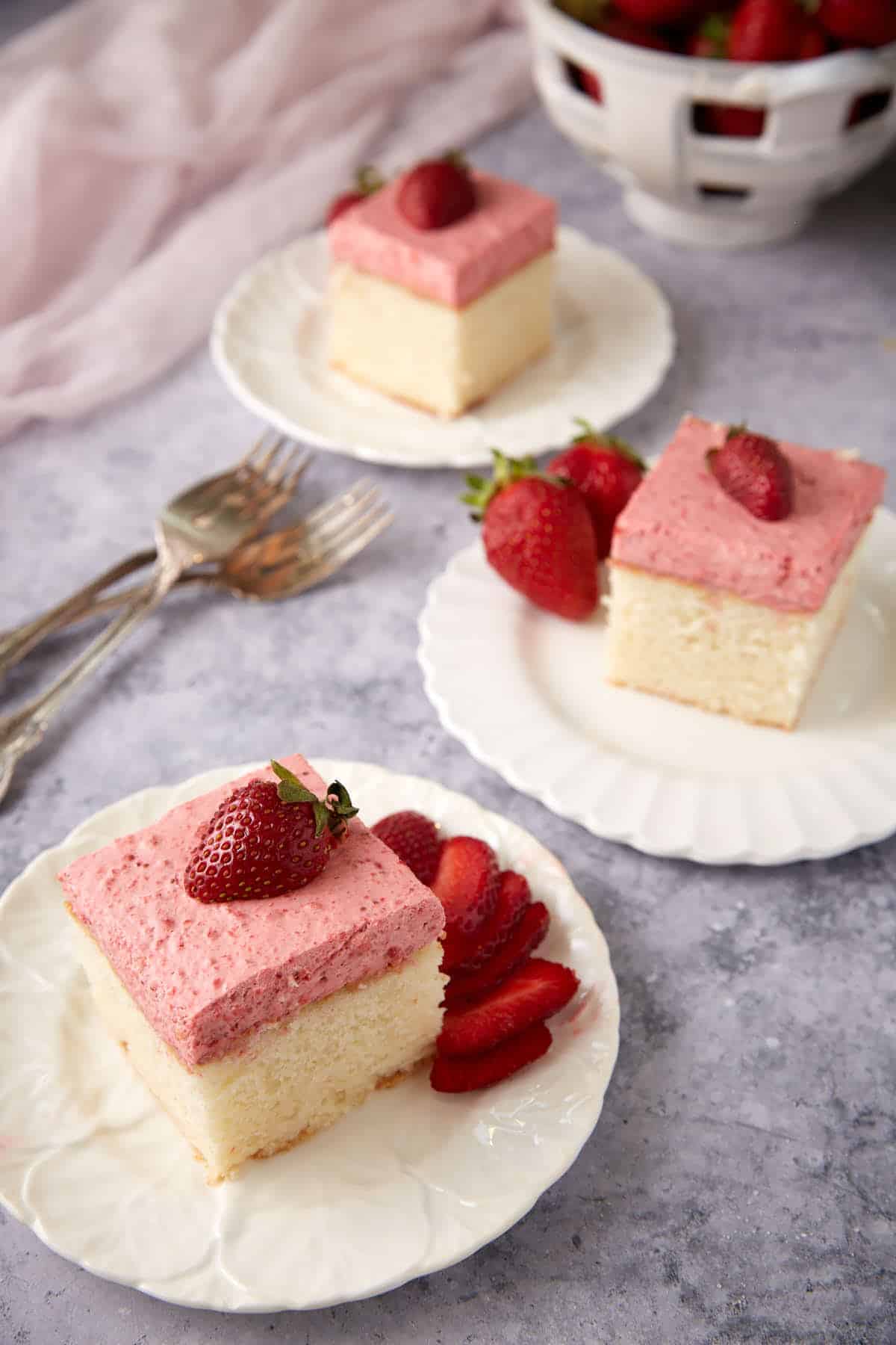 three slices of strawberry mousse cake on white plates.