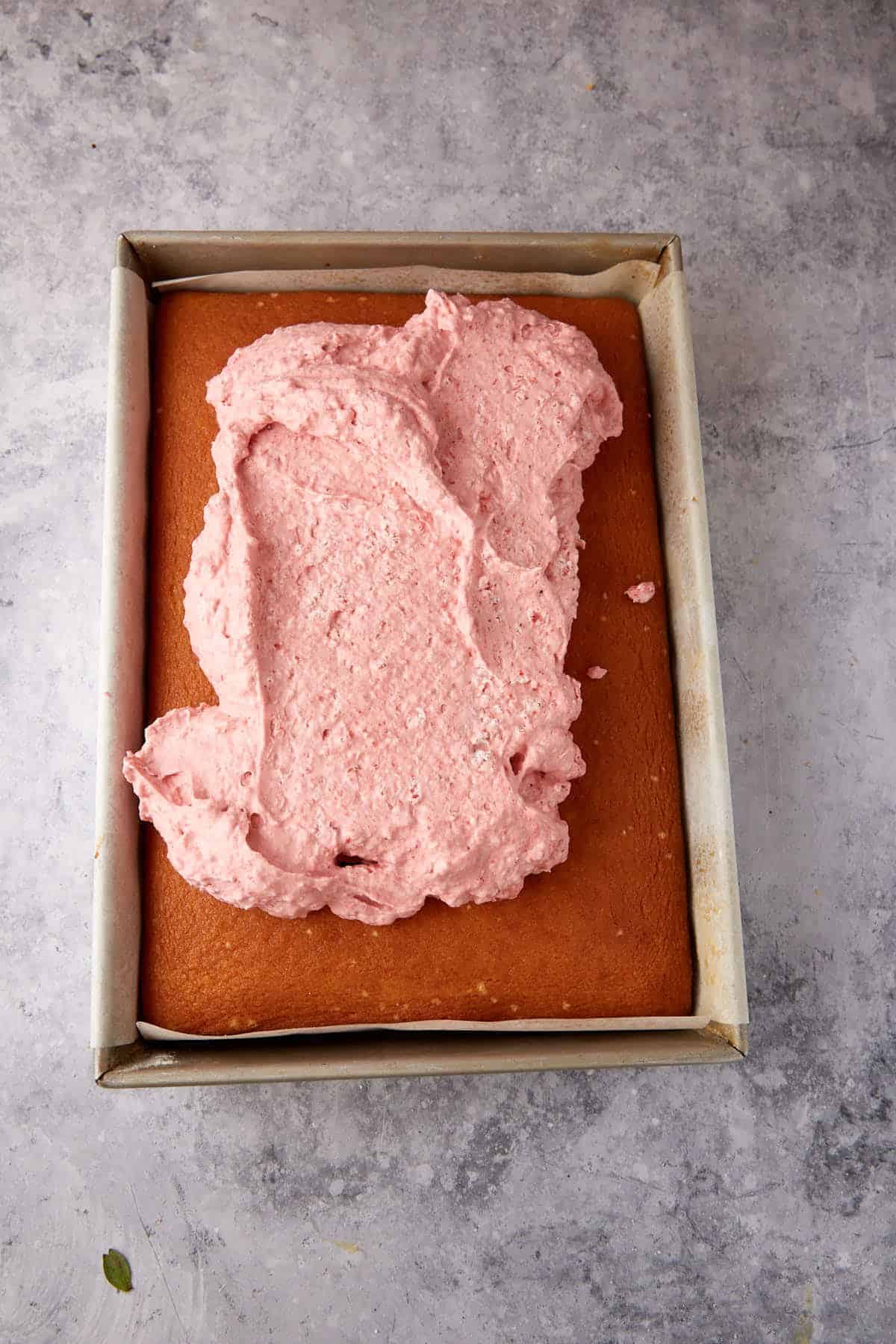 Strawberry mousse being spread on a cake.
