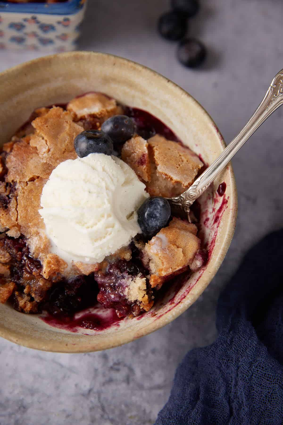 A bowl of blueberry cobbler with ice cream.
