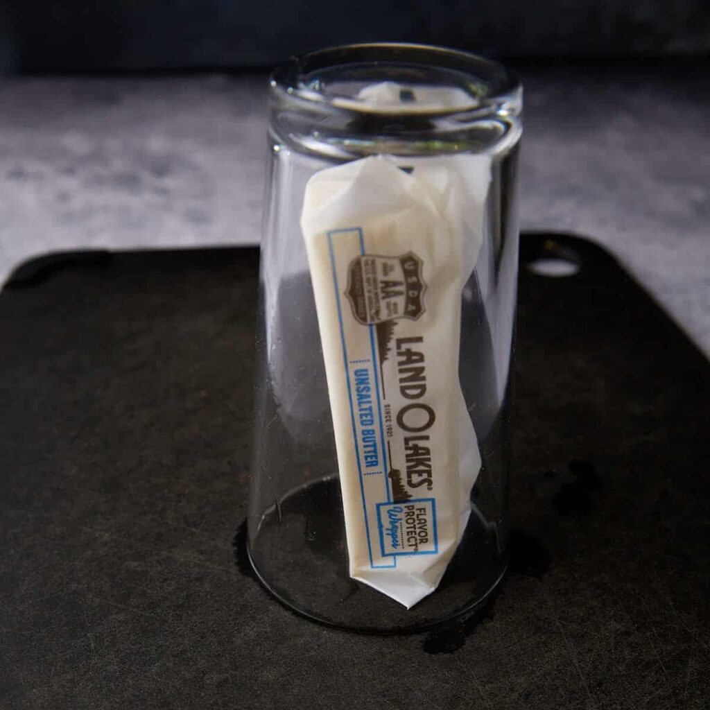 A stick of butter under a glass.