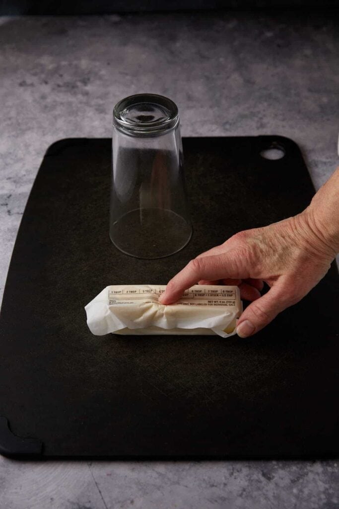 A finger pushing a stick of butter.