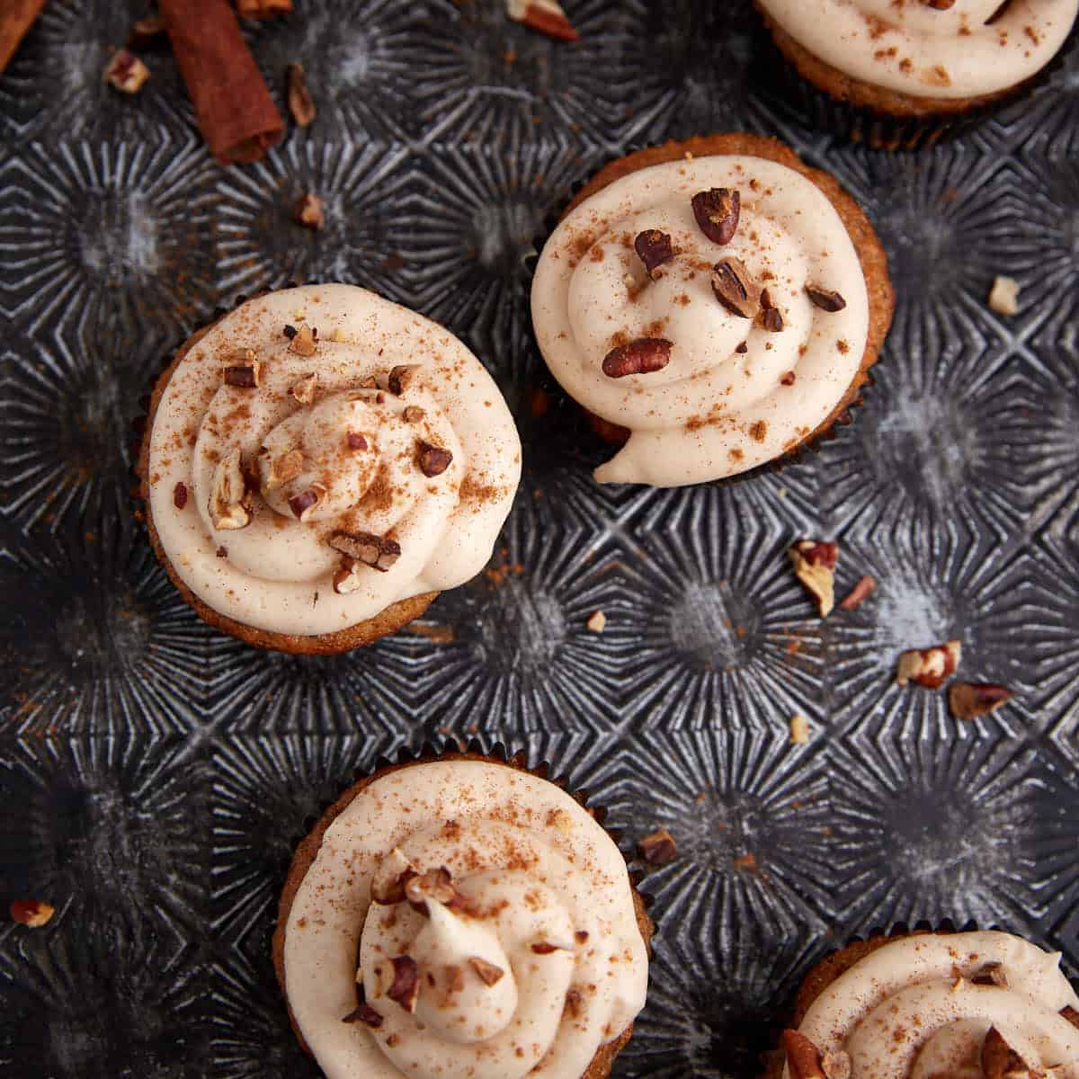 Cupcakes topped with brown sugar cream cheese frosting and pecans.