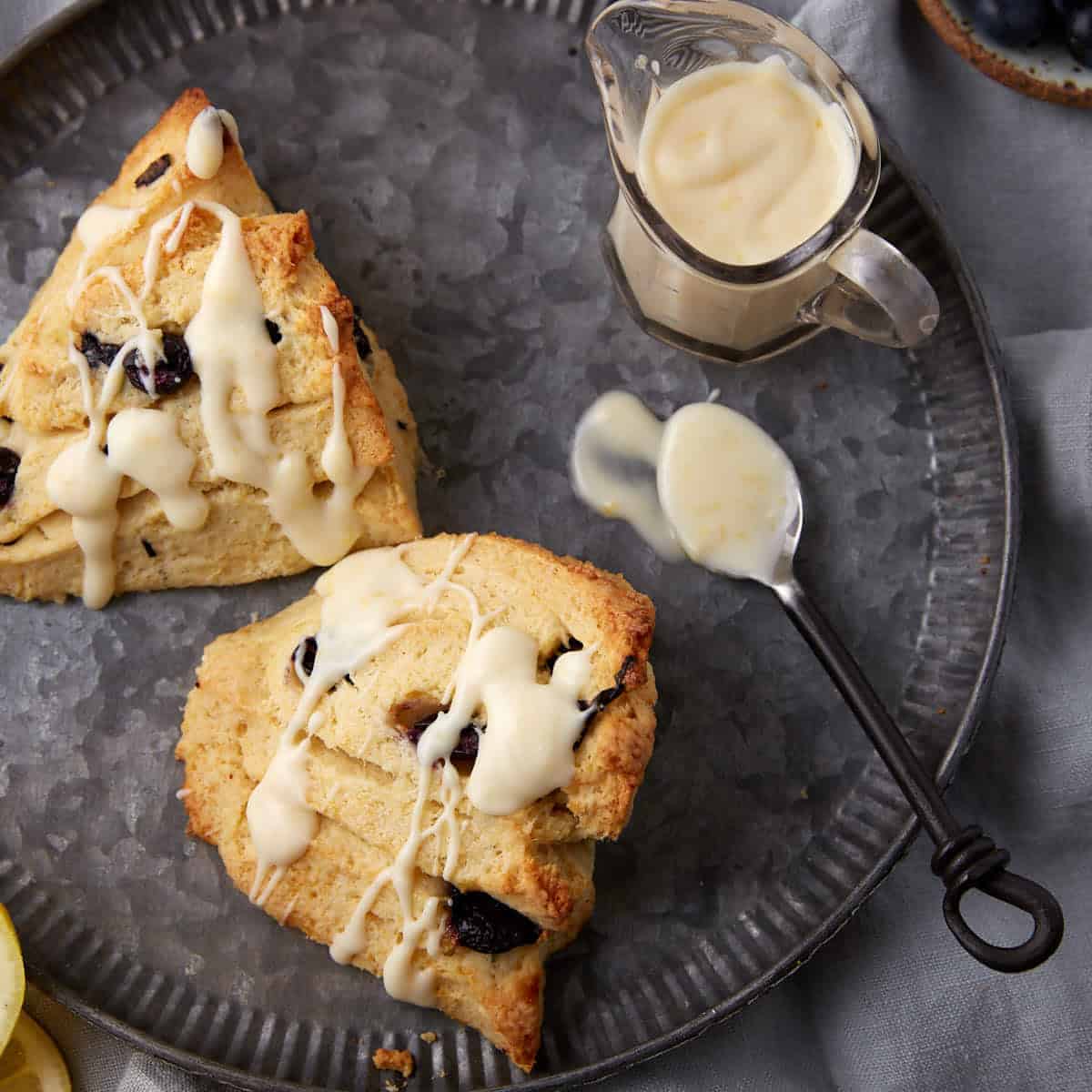 Blueberry scones on a plate with lemon glaze.