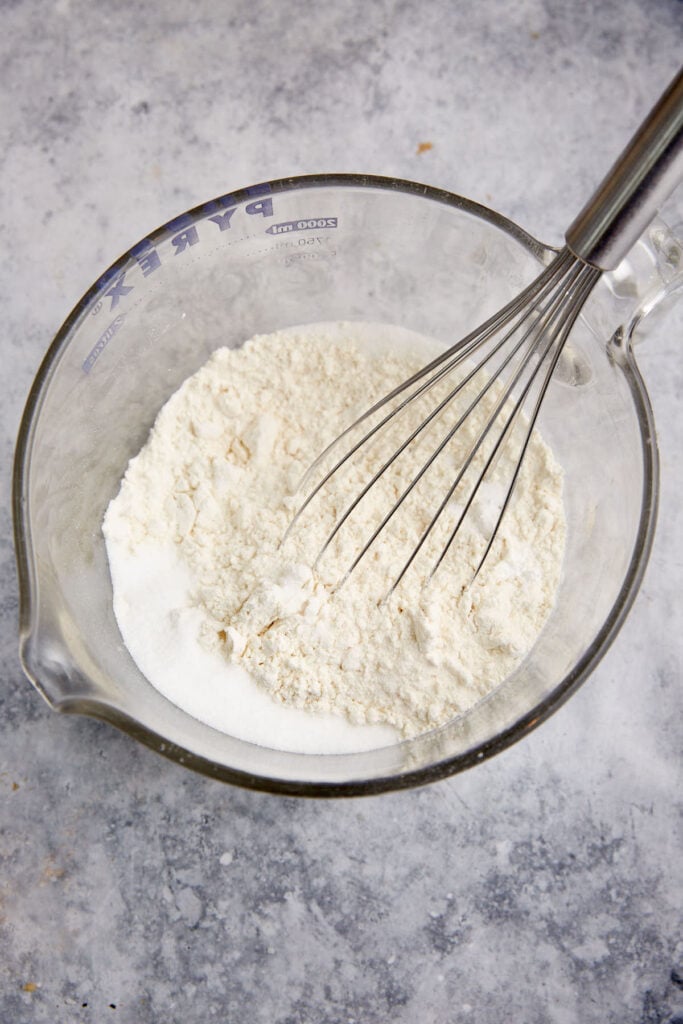 A bowl of the dry ingredients with a whisk.