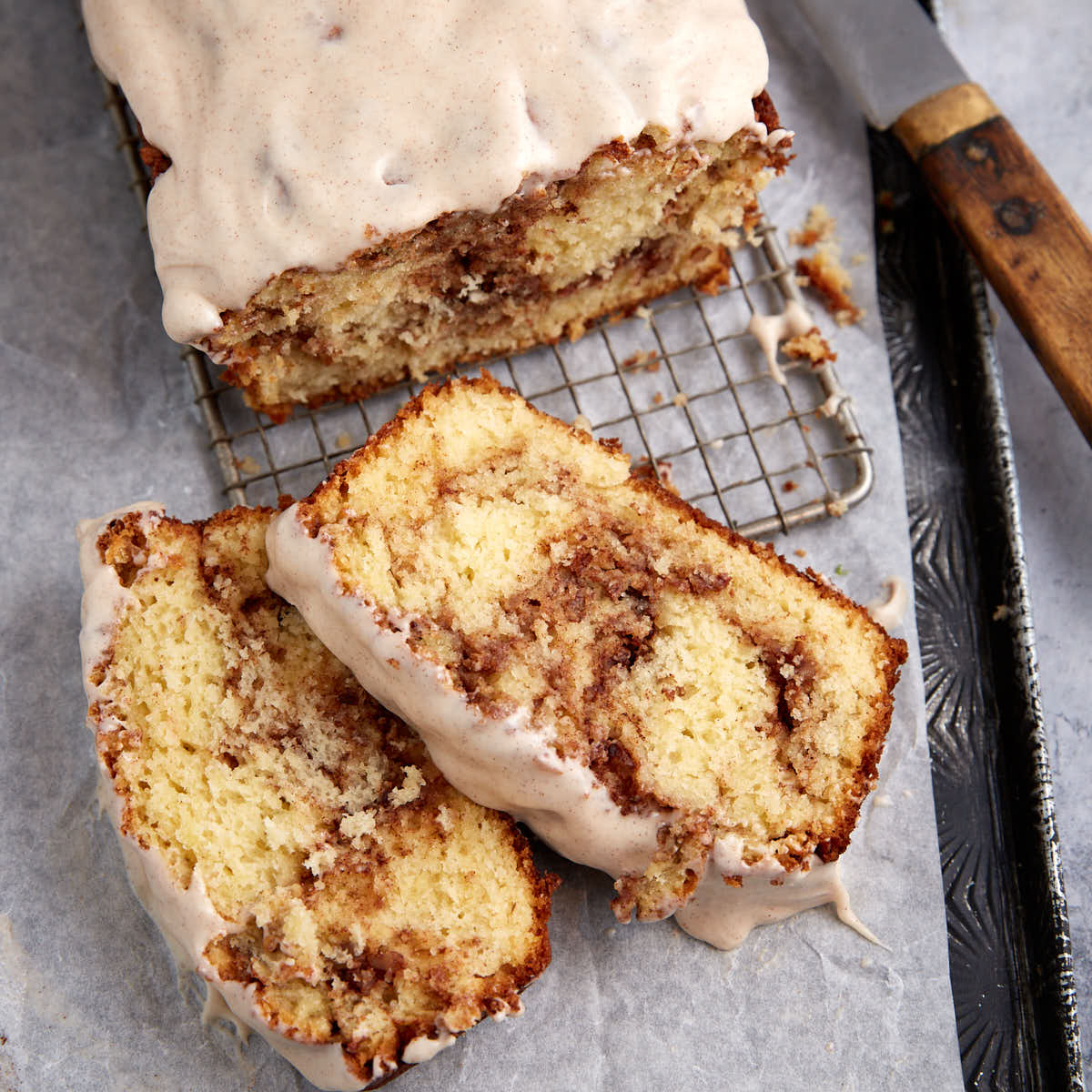 A sliced cinnamon swirl bread topped with frosting.