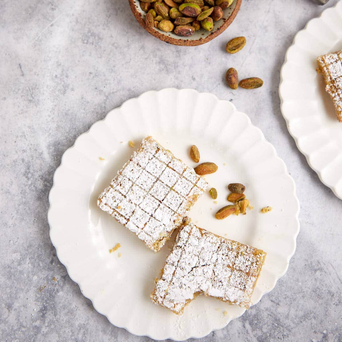 Lemon pistachio bars on a white plate.