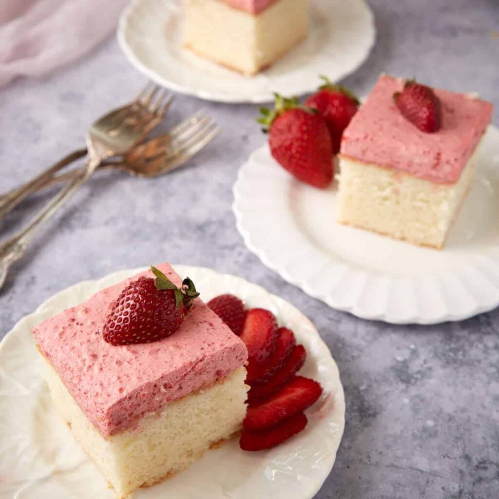 Slices of strawberry mousse cake on white plates.