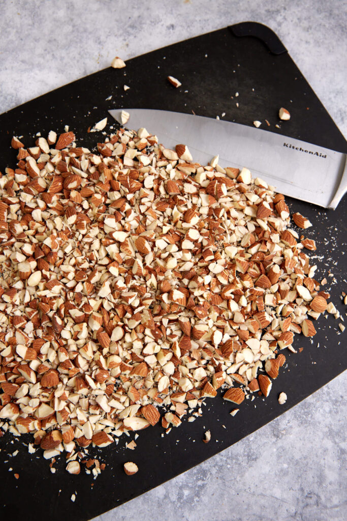 A cutting board with chopped almonds.