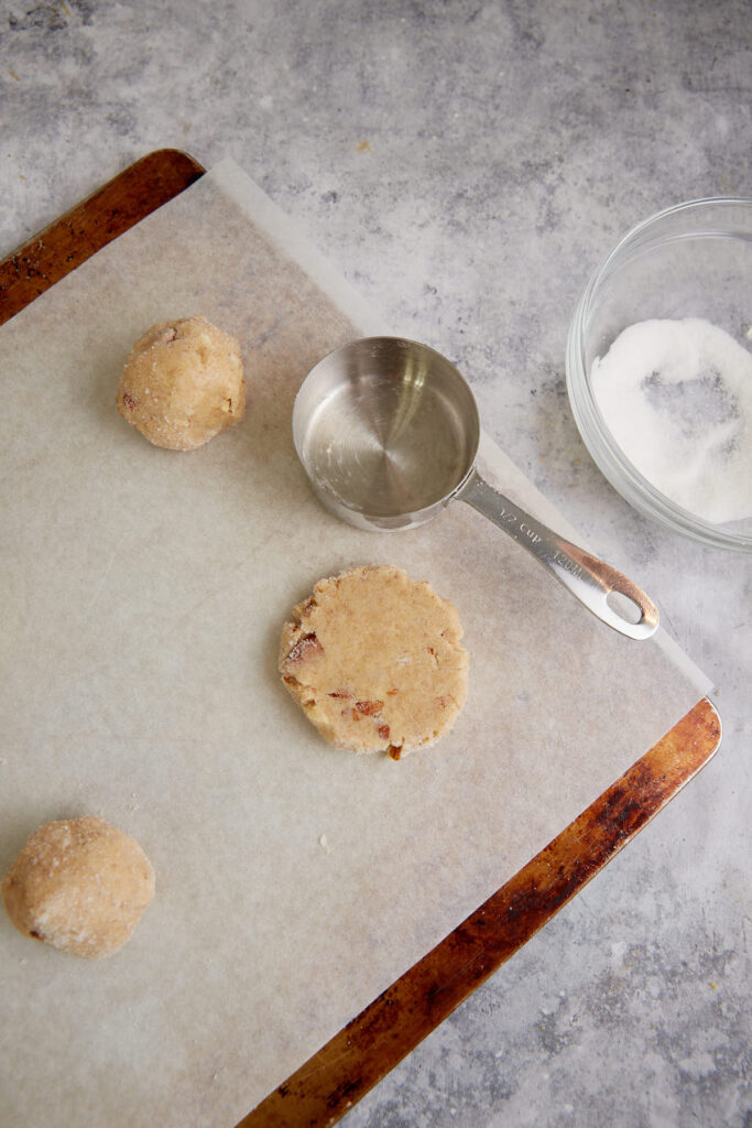 Cookies flattened before baking on a cookie sheet.
