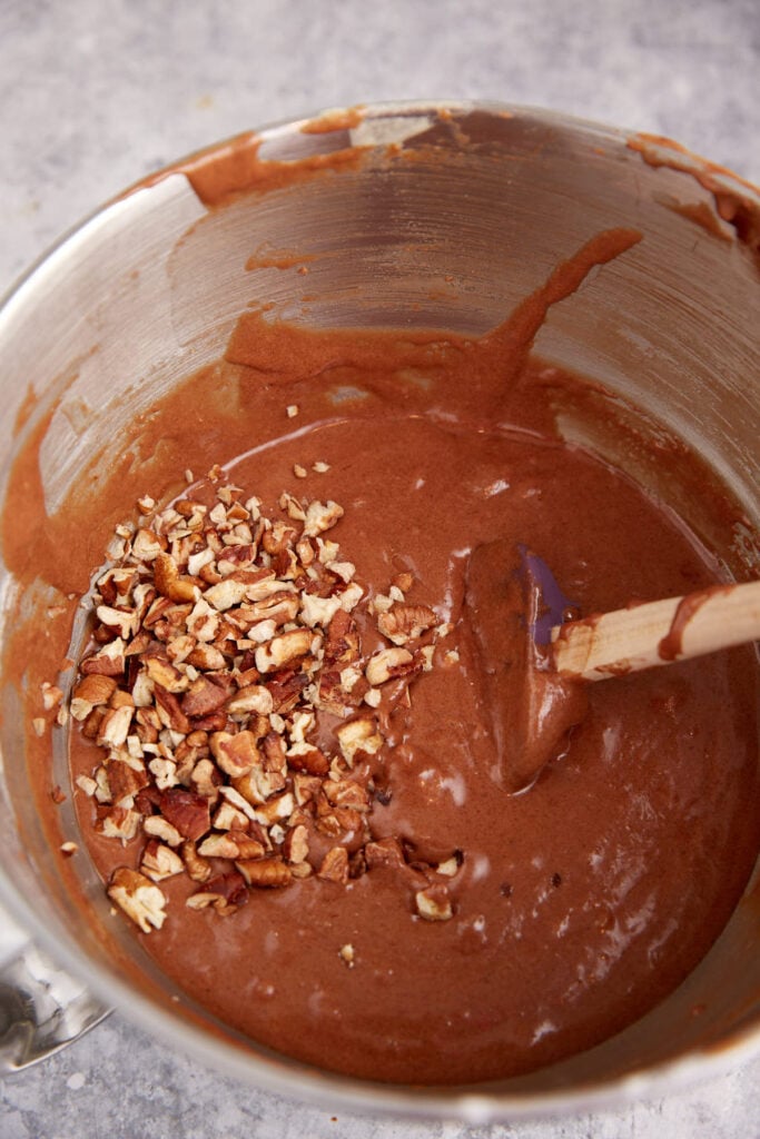 Pecans added to brownie batter in a mixing bowl.