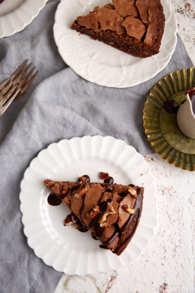 Two slices of chocolate brownie pie with chocolate syrup poured over the top.