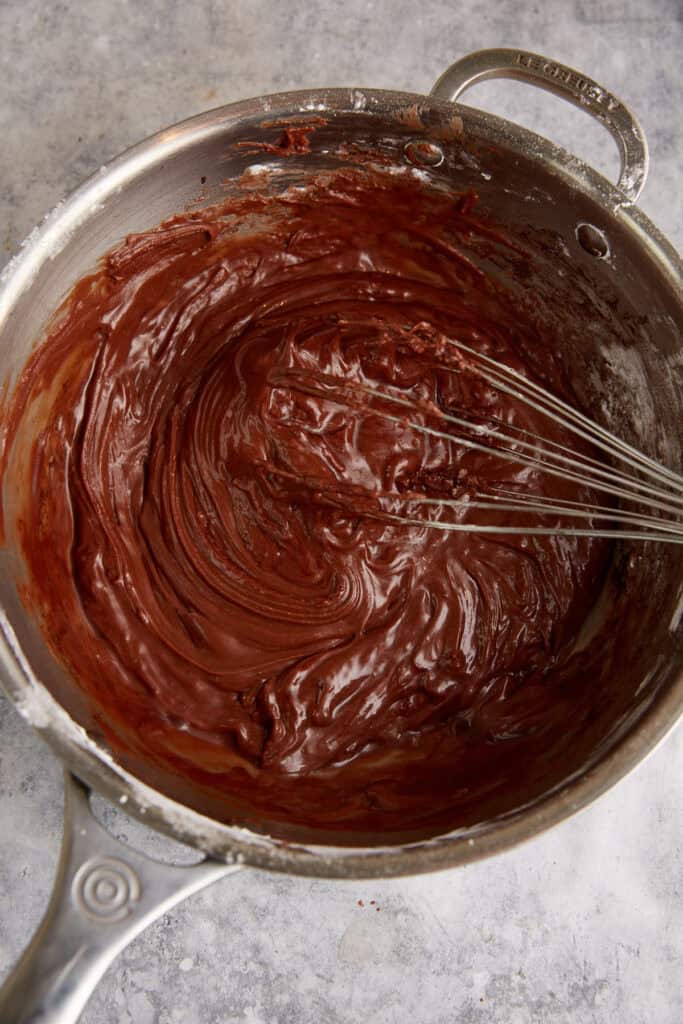 Frosting being whisked in a saucepan.