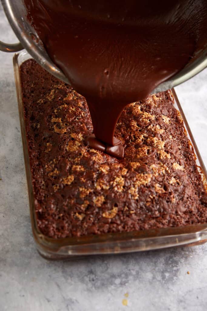 Frosting being poured over a hot chocolate cake.