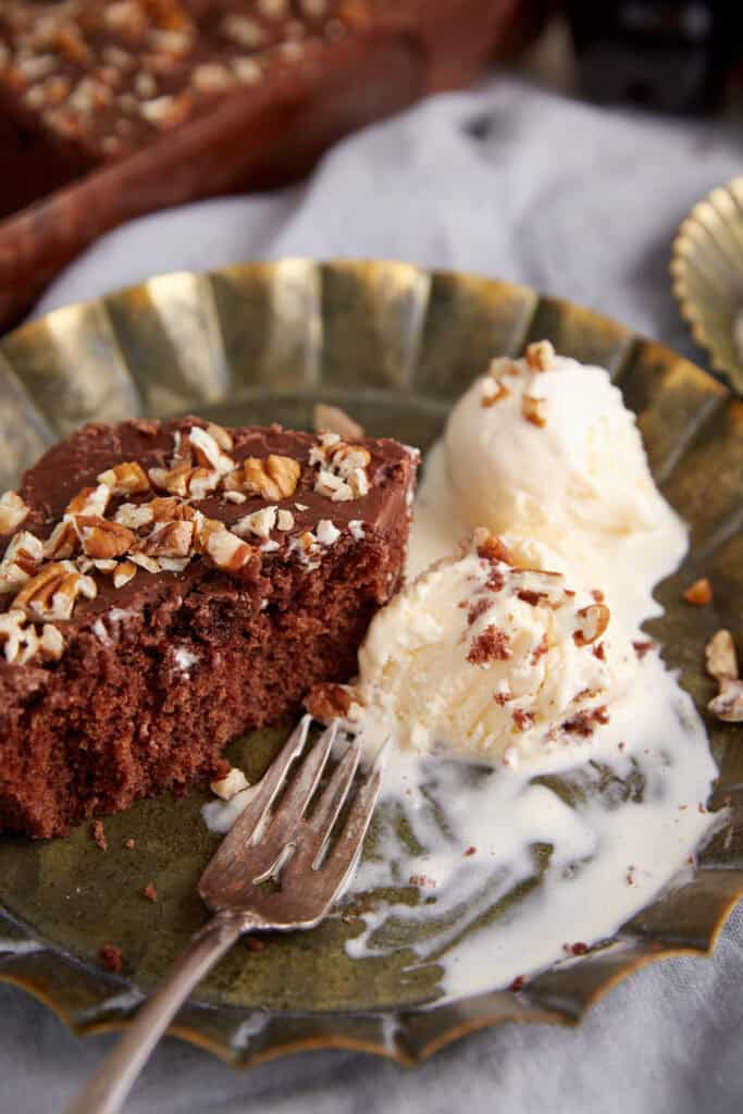 A piece of coca-coaklacake partially eaten next to ice cream.