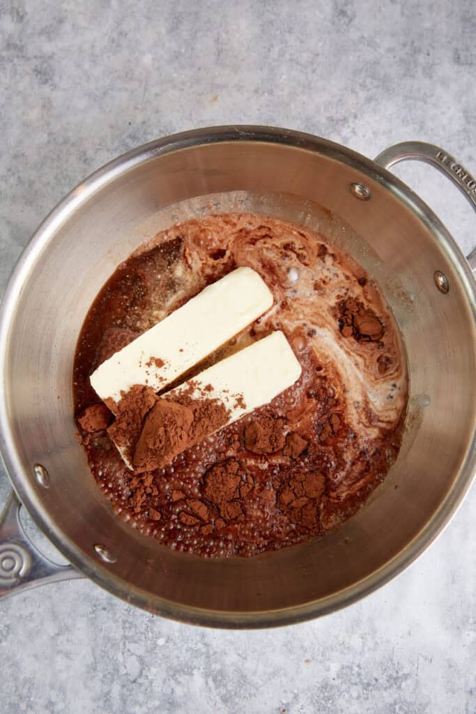 Butter cocoa and coca-cola added to a saucepan.