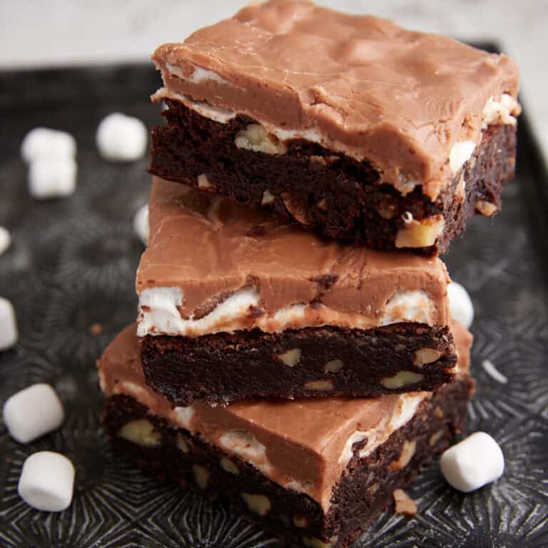 Three chocolate brownies stacked on a tray with marshmallows.