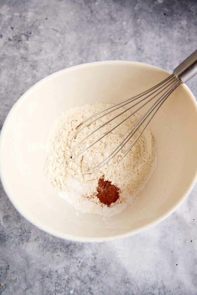 A bowl of dry ingredients with a whisk.