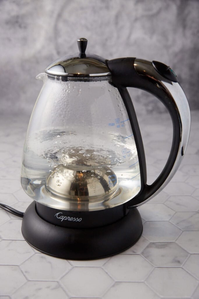 A tea kettle with water just coming to a boil.