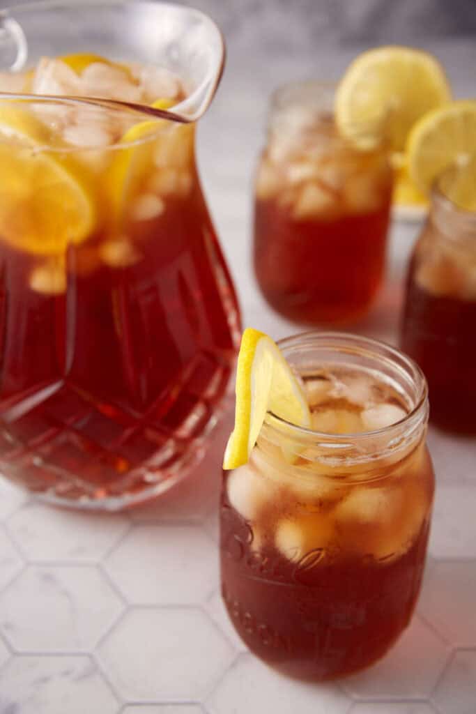 A pitcher of sweet tea next to glasses of tea.