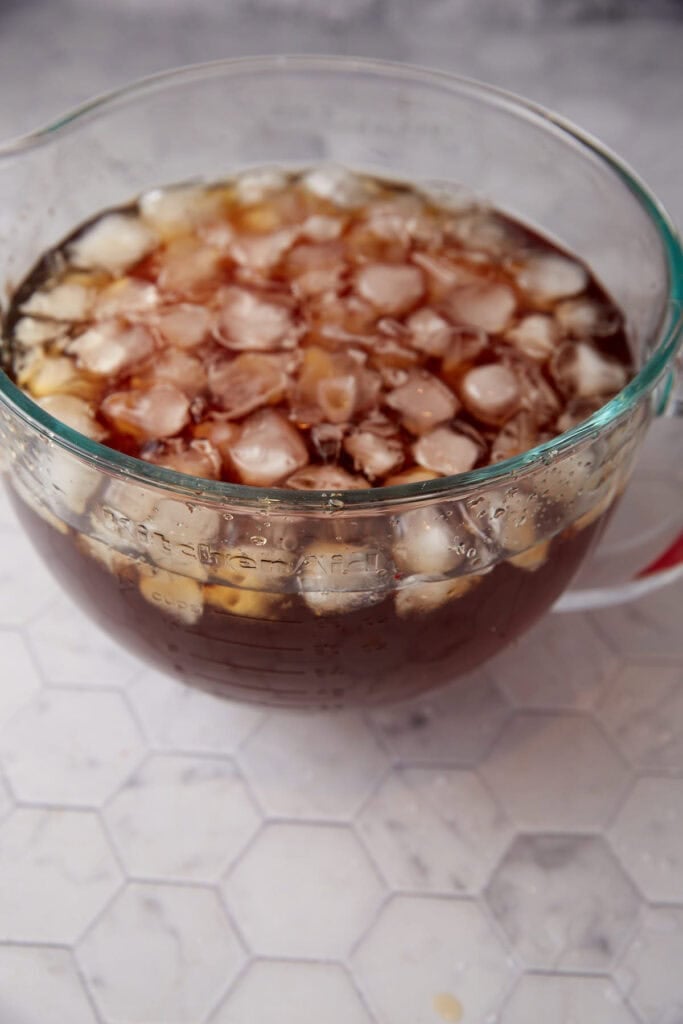 A gallon pitcher with sweet tea and ice cubes.