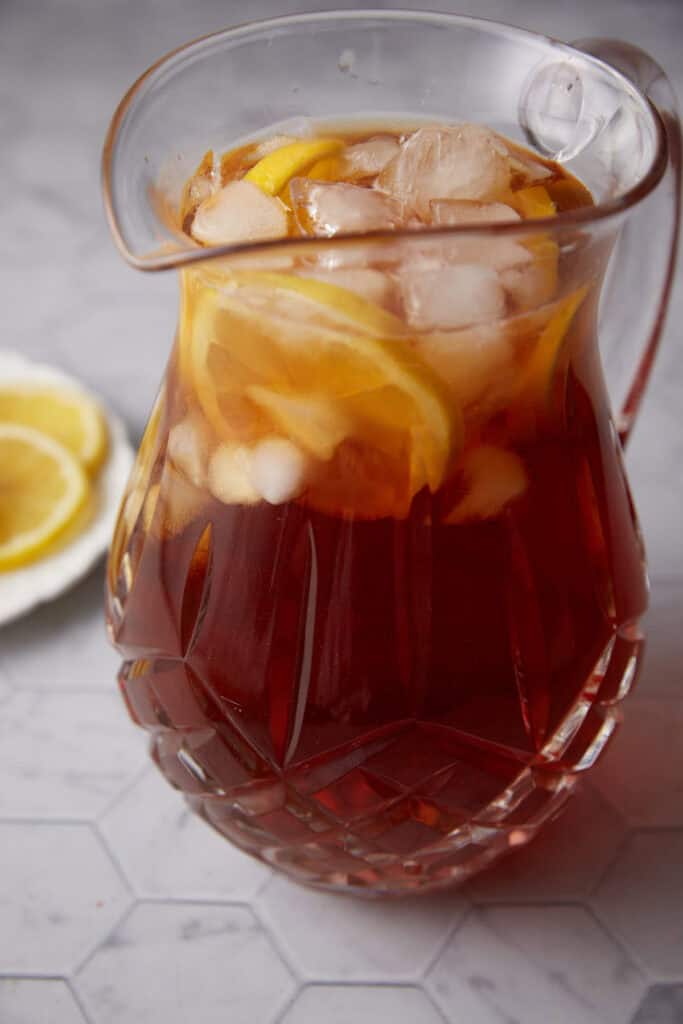 A glass pitcher with sweet tea and lemons.