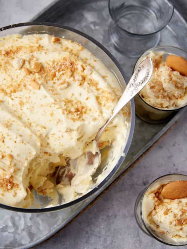 A bowl of banana pudding with a spoon in it next to two servings.