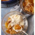 A dish of peach cobbler with ice cream.