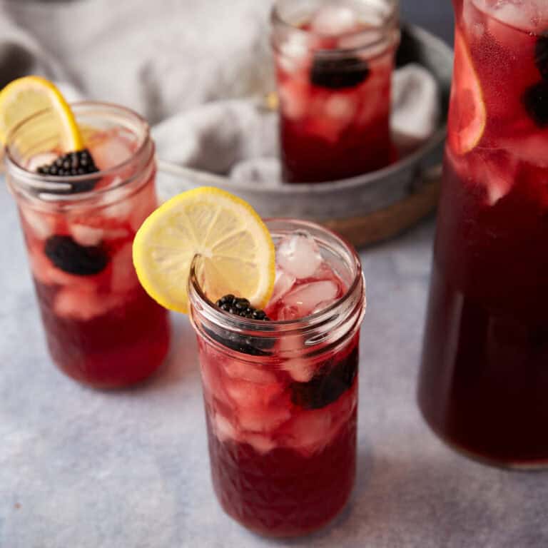 Glasses of blackberry tea next to a pitcher of tea.