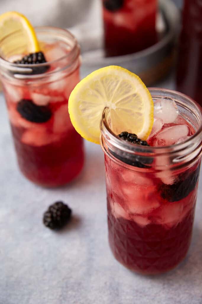 Blackberry iced tea in glasses with lemon slices.