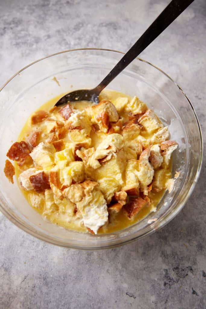 A bowl of bread cubes with the egg mixture added. 