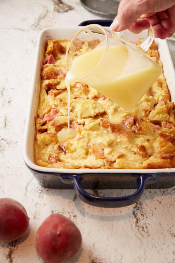 A glaze being poured over peach cobbler bread pudding. 