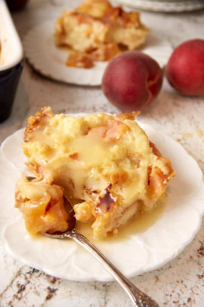 A serving of peach bread pudding on a plate with a fork. 