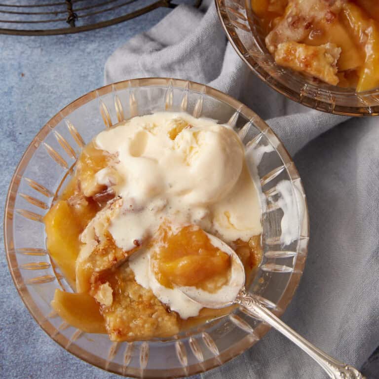 A bowl of peach cobbler with ice cream on top.