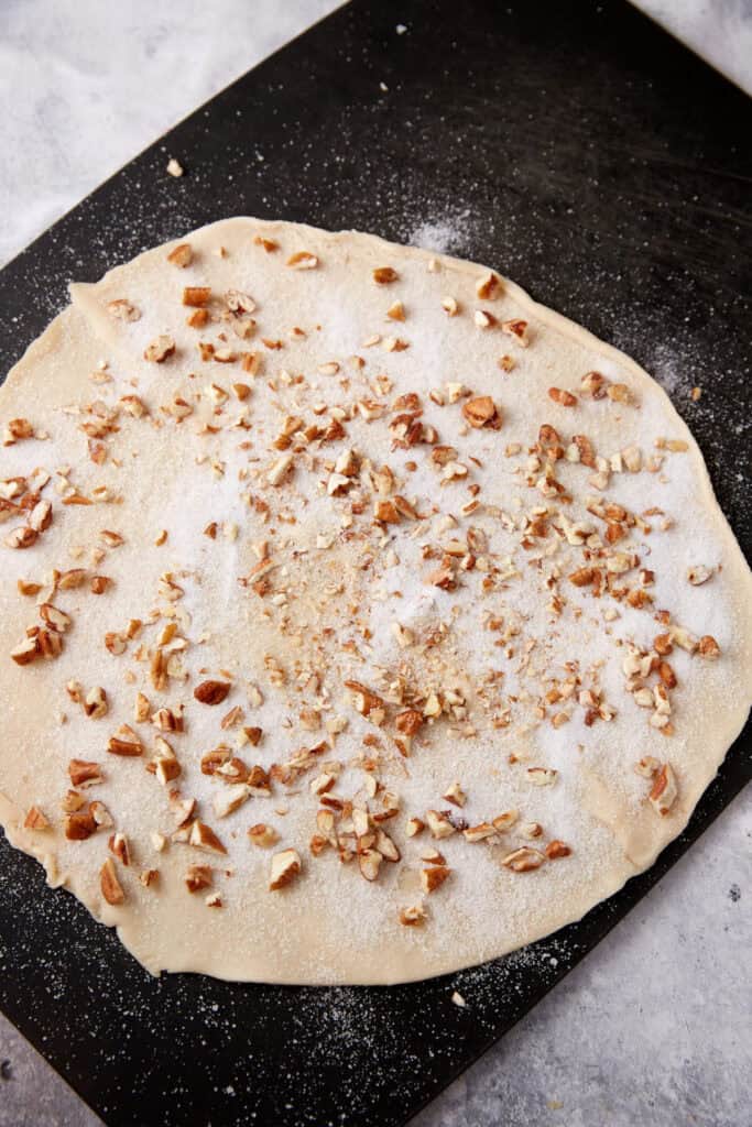 Pecans and sugar sprinkled over a pie crust.