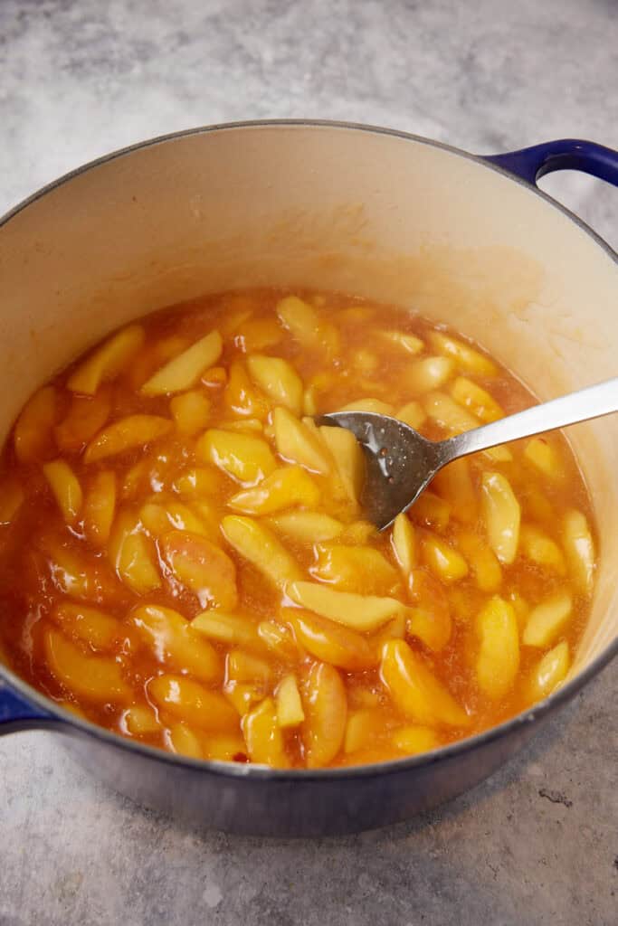 A dutch oven with cooked peaches.