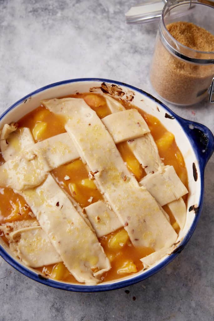 Strips of pie crust on the top of a peach cobbler.
